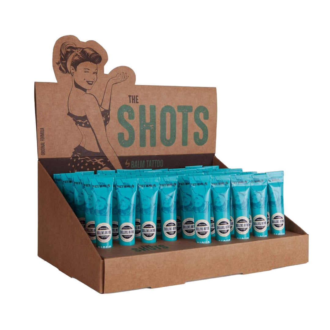 Display box of Balm Tattoo Shots Original Formula – a collection of 8g tubes designed for tattoo aftercare, featuring a vintage-inspired pin-up girl and eco-friendly packaging.