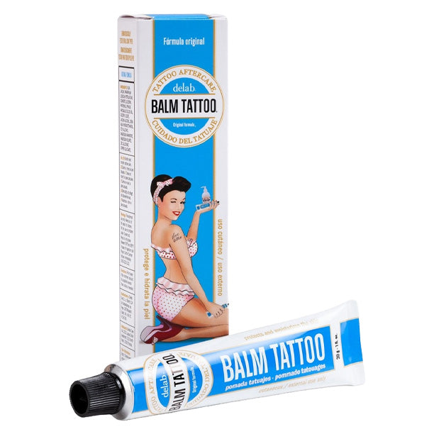 Tube and box of Balm Tattoo Original Formula tattoo aftercare balm, featuring a retro pin-up girl design, ideal for promoting tattoo healing with Panthenol 5% and a skin-nourishing vegan formula.